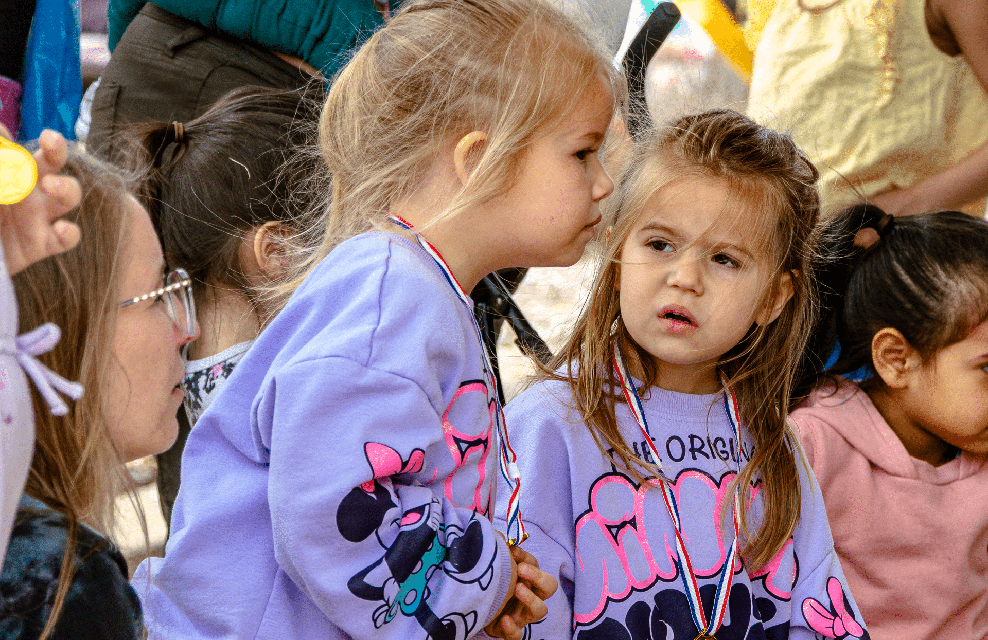 Two young friends in matching shirts and medals, smiling together among our welcoming church family outdoors. - Muscatine Church of Christ