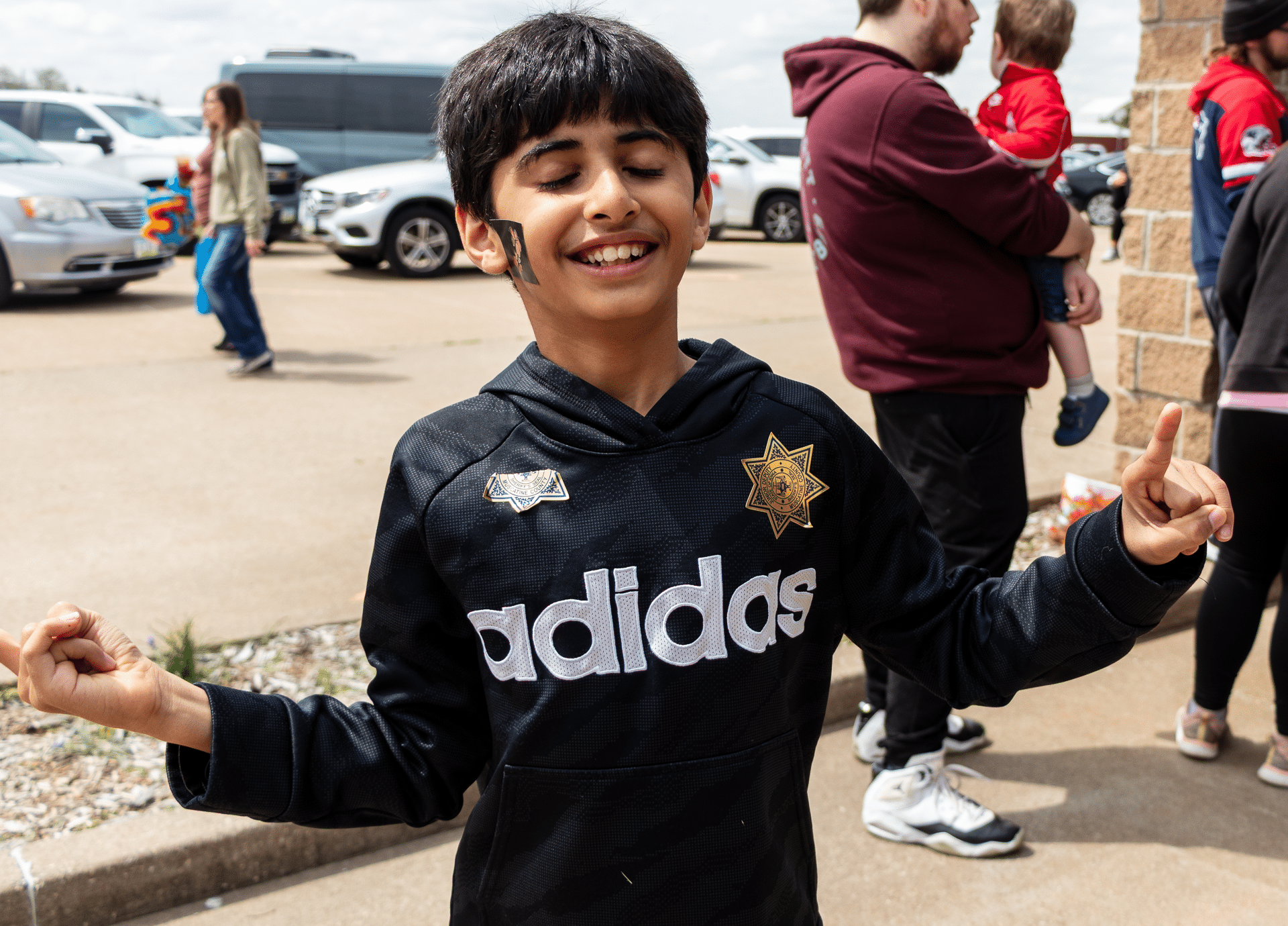 A joyful boy smiles with raised hands, sharing hope and welcome outside among friends at Muscatine Church of Christ. - Muscatine Church of Christ