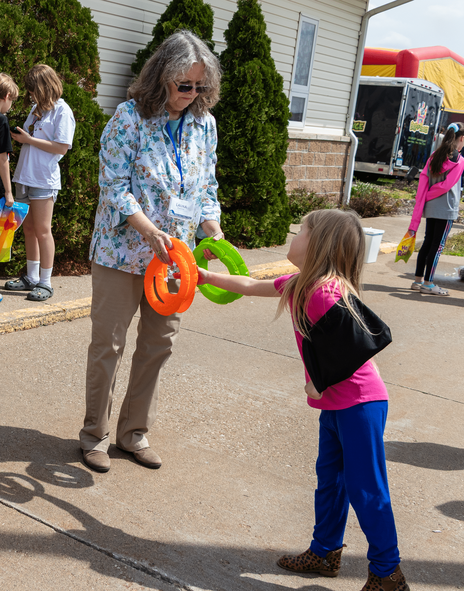 A woman encourages a young girl at an outdoor ring toss, sharing smiles and hope with our church family community. - Muscatine Church of Christ