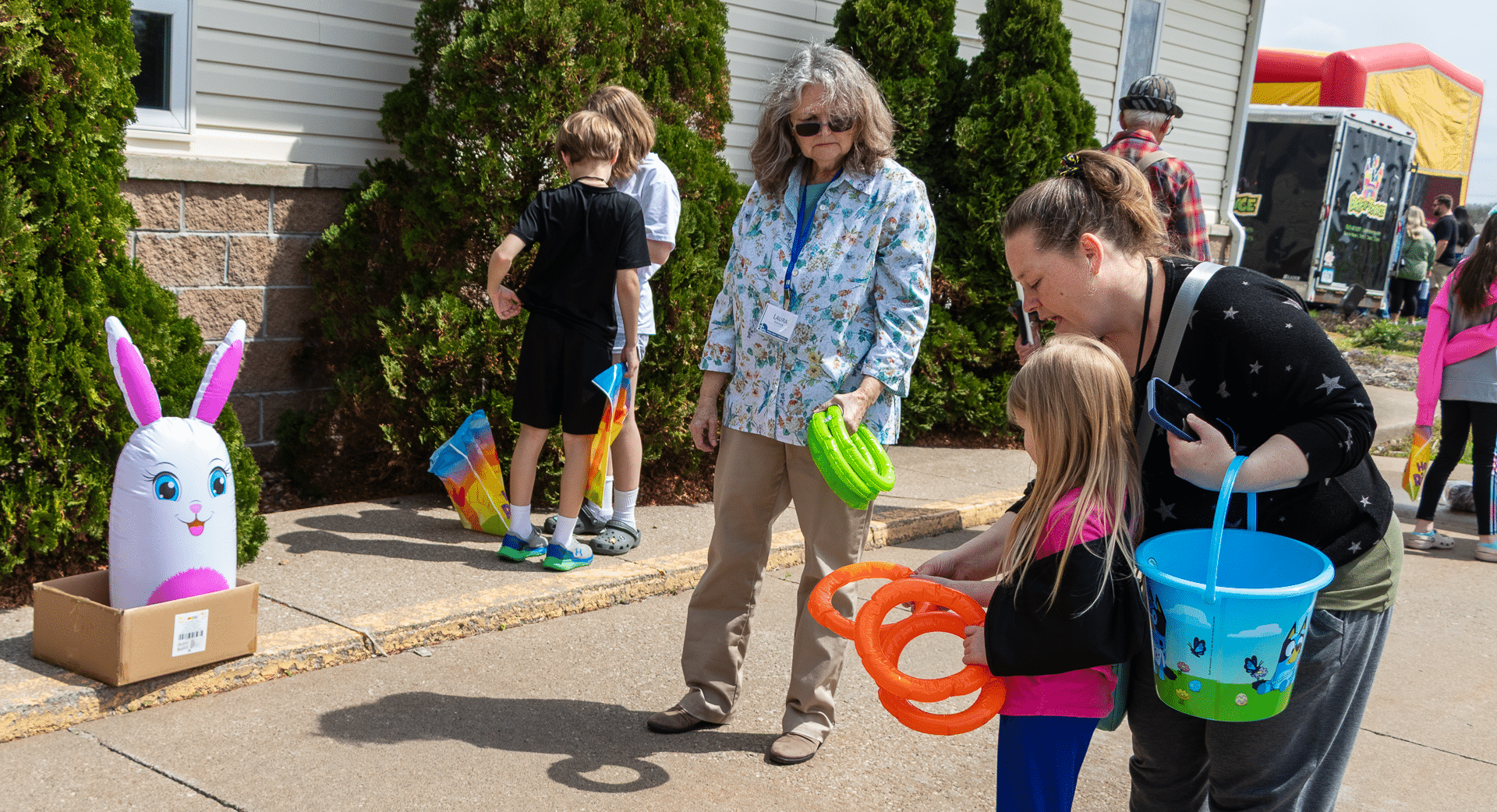 Smiling adults and kids share joy and hope together, playing a cheerful bunny ring toss at our church event. - Muscatine Church of Christ