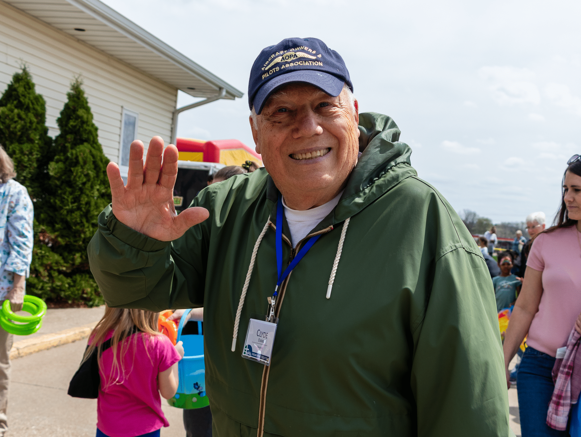 A friendly man waves and smiles outdoors, surrounded by our welcoming church family of all ages. - Muscatine Church of Christ