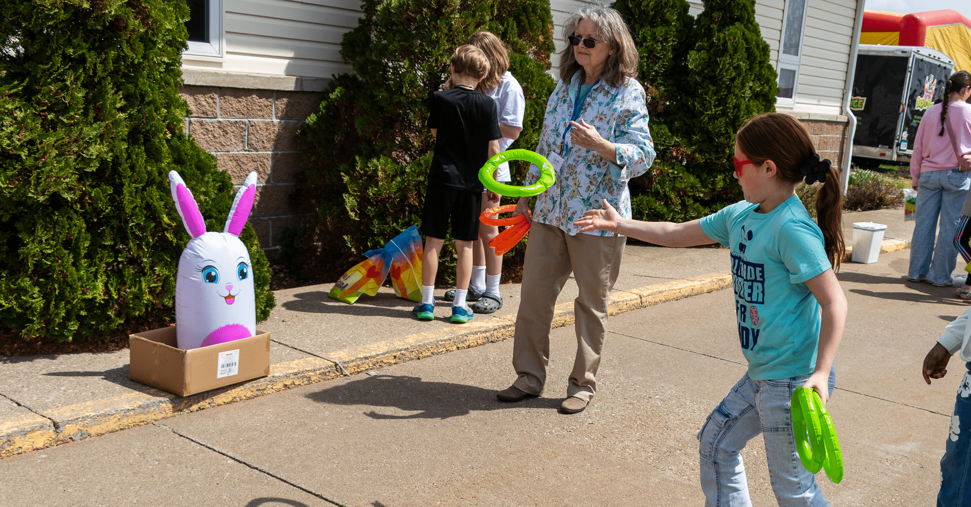 Children and adults share laughter outdoors, playing a ring toss game together on a bright, hope-filled day. - Muscatine Church of Christ
