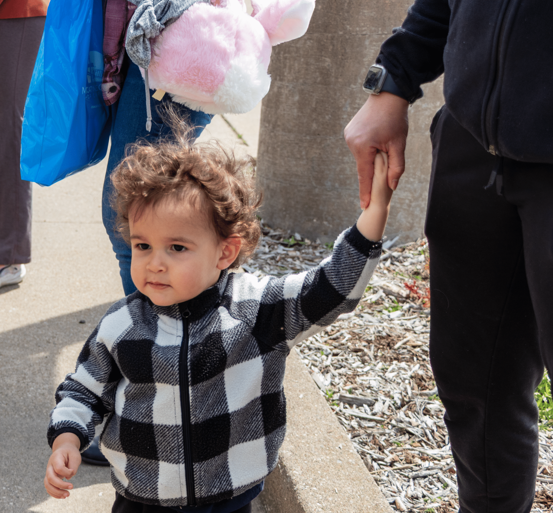A child holds an adult’s hand as they walk together outside, sharing warmth, hope, and community. - Muscatine Church of Christ