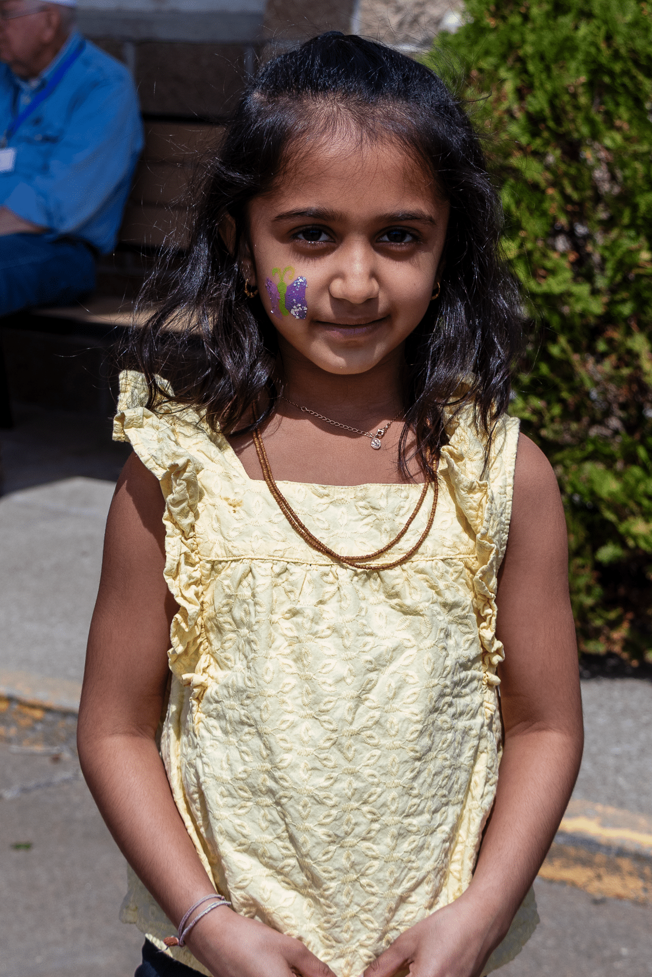 Smiling young girl with a butterfly face paint enjoys a sunny day outdoors—celebrating joy and community together. - Muscatine Church of Christ