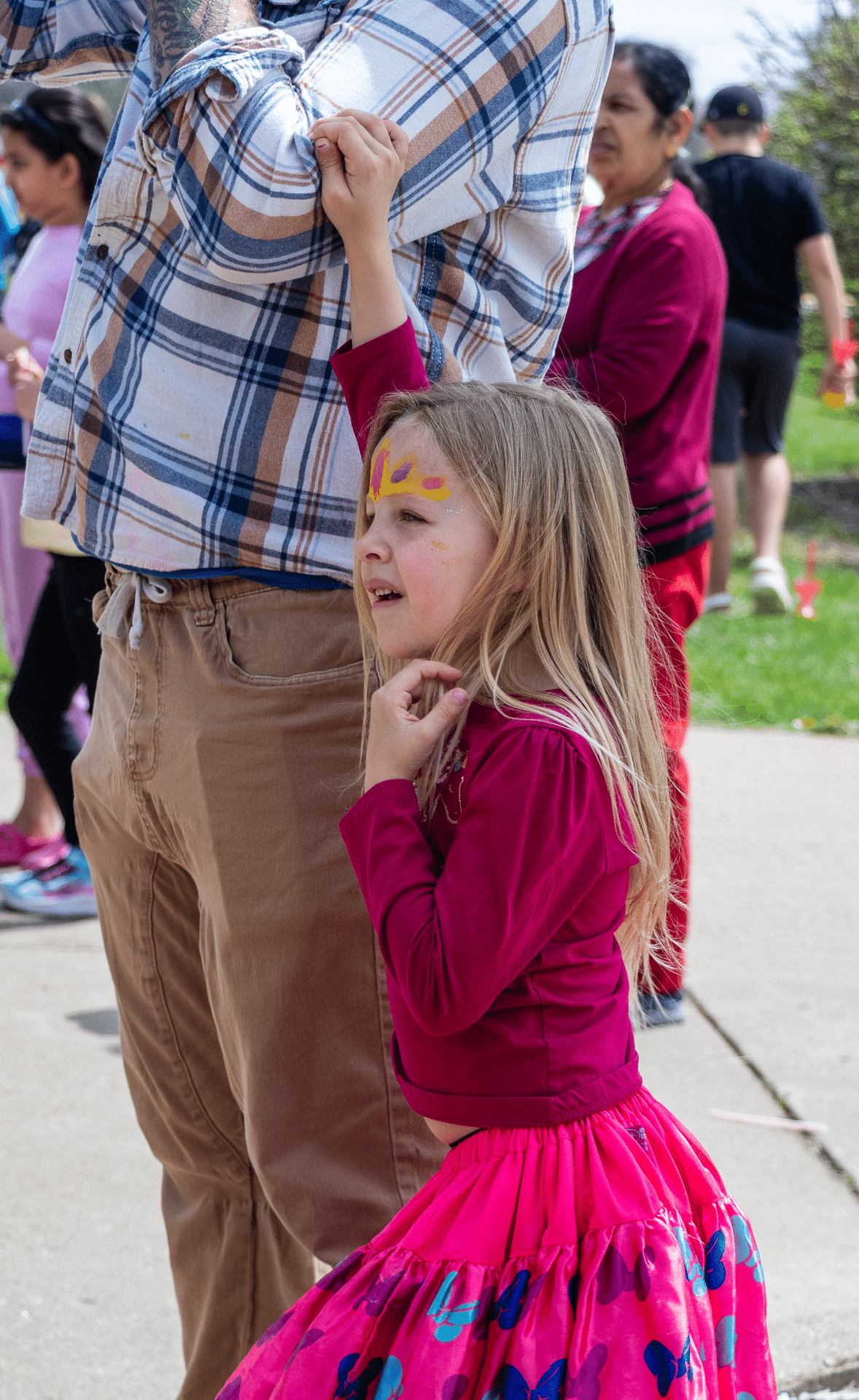 A joyful girl with face paint and a bright skirt holds a caring hand, surrounded by our welcoming church family. - Muscatine Church of Christ