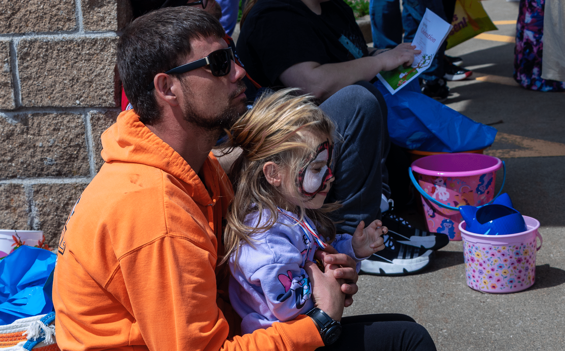 A caring adult hugs a joyful, face-painted child at our outdoor gathering—community and hope all around. - Muscatine Church of Christ