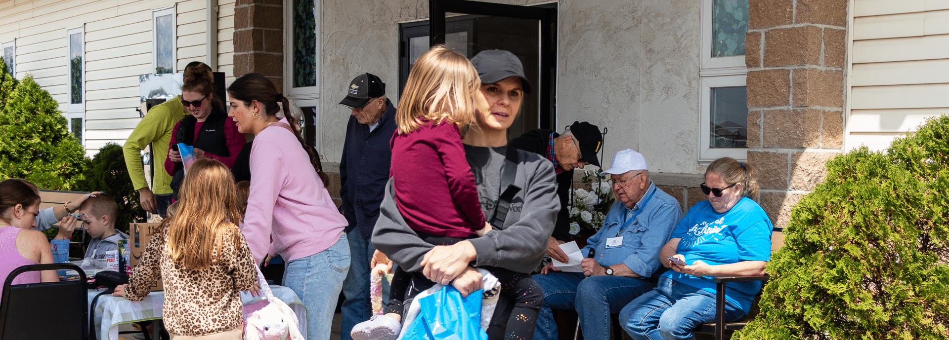 A welcoming group of all ages gathers outside, sharing smiles and hope in our church community. - Muscatine Church of Christ