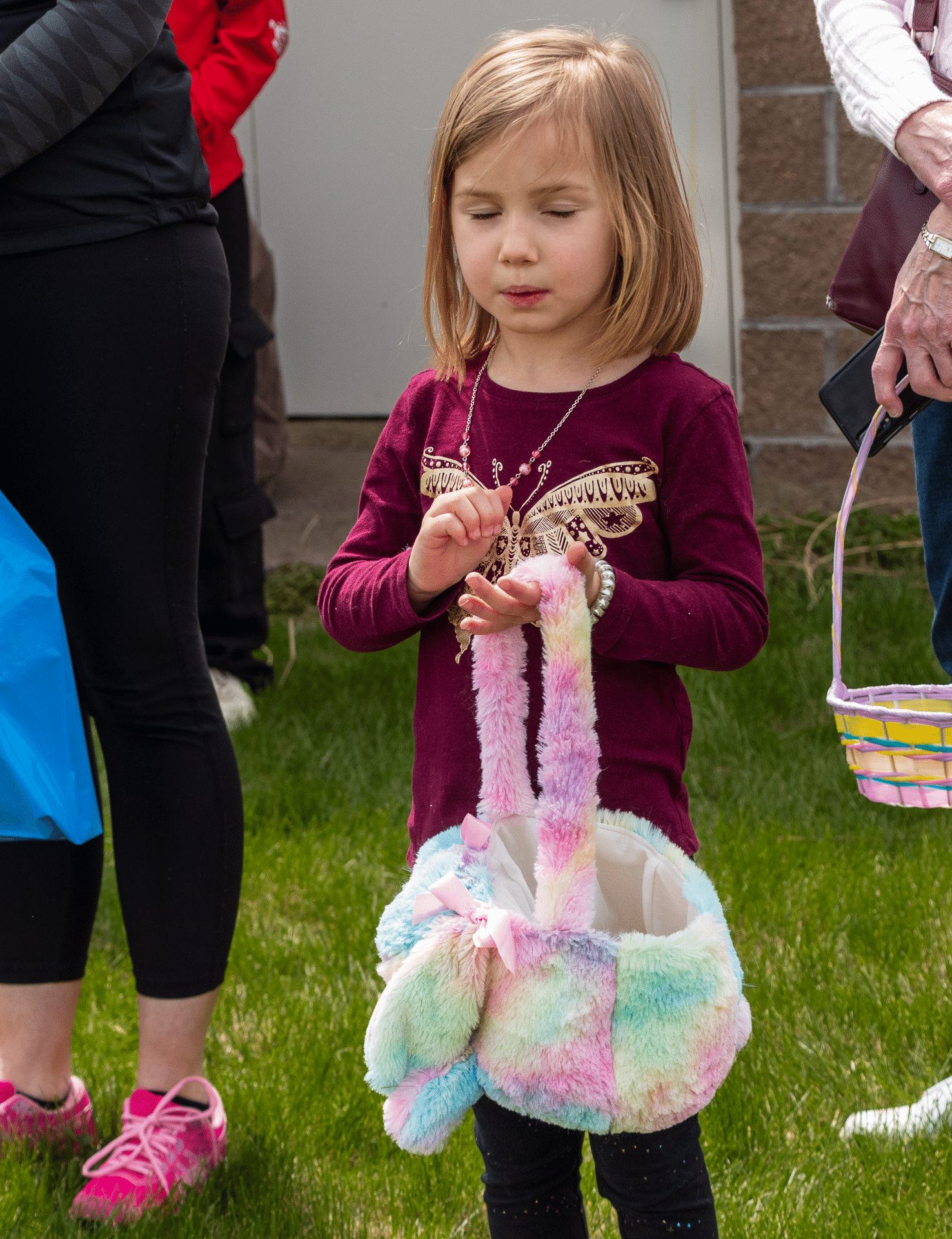A joyful child with a pastel basket stands among friends—everyone is welcome in our caring church family. - Muscatine Church of Christ