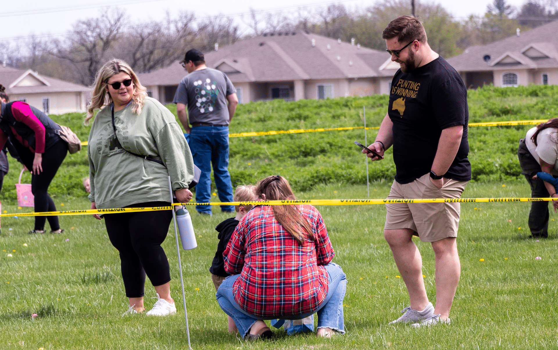 A community gathers on a sunny lawn, connecting and sharing hope—with welcoming homes in the background. - Muscatine Church of Christ