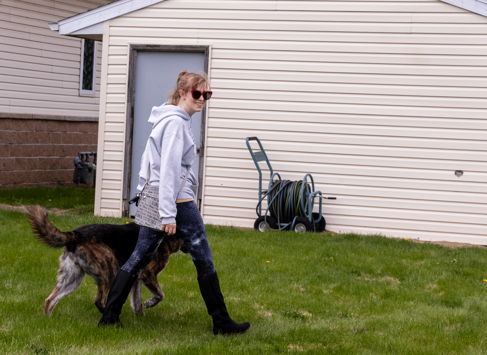 A woman walks her dog on the grass, a reminder of the hope and warmth found in community togetherness. - Muscatine Church of Christ