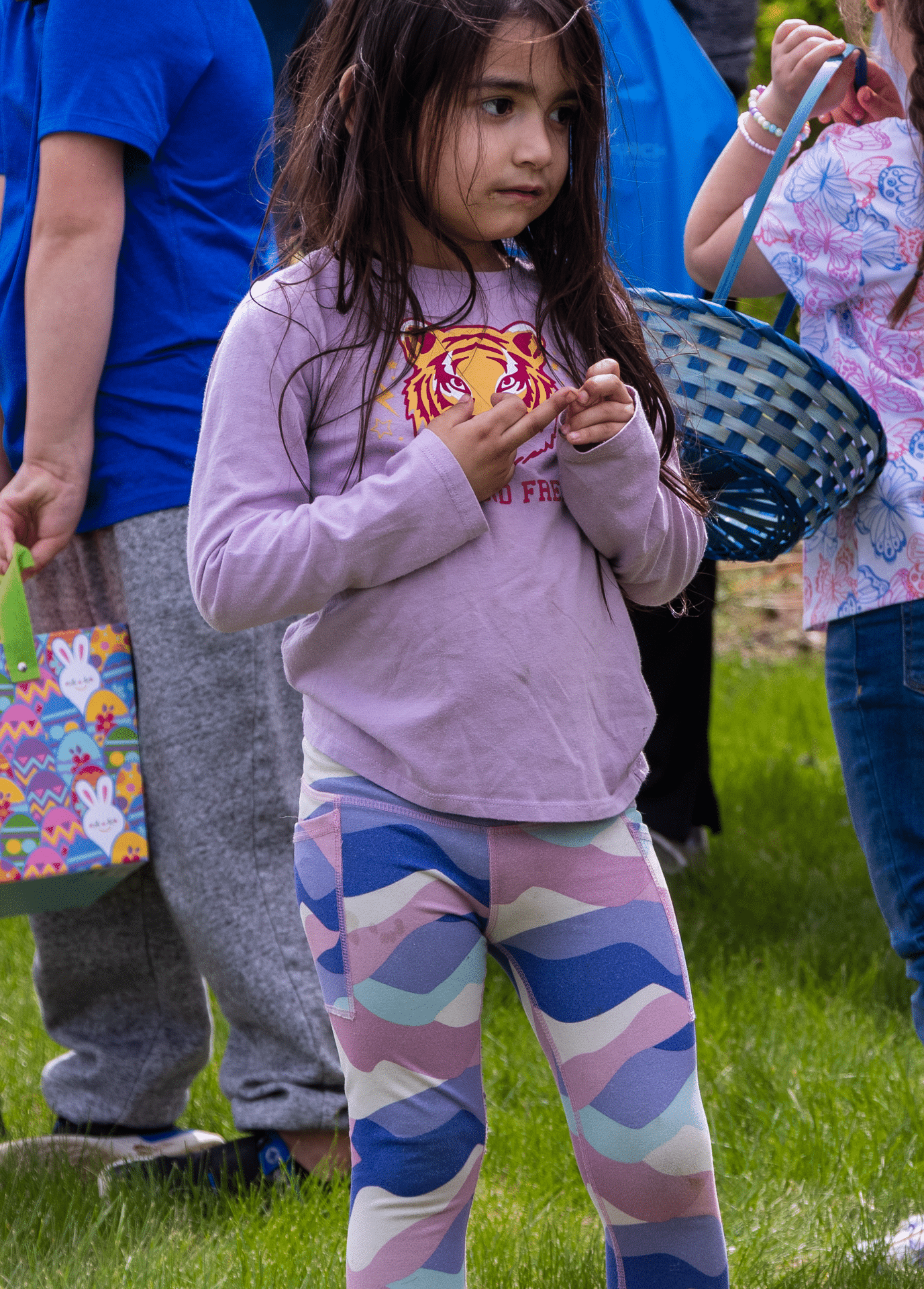 A young girl smiles on the grass, surrounded by Easter baskets and friends—celebrating hope and community together. - Muscatine Church of Christ