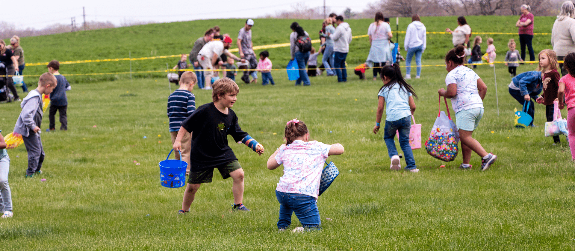 Children joyfully hunt for Easter eggs on the grass as our church family gathers in warmth and hope nearby. - Muscatine Church of Christ