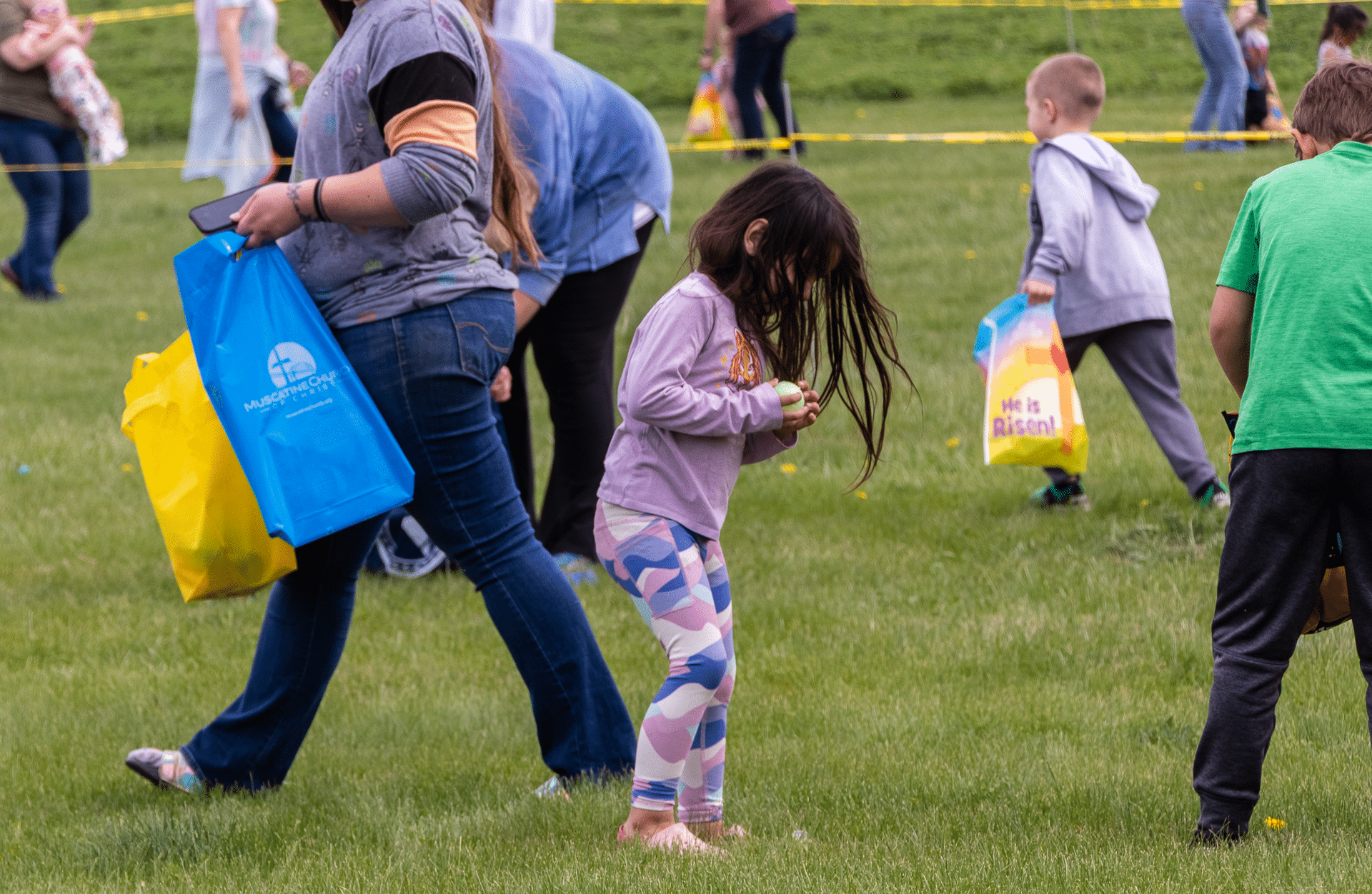 Families and friends joyfully join an outdoor egg hunt—sharing laughter, hope, and community on a sunny day. - Muscatine Church of Christ