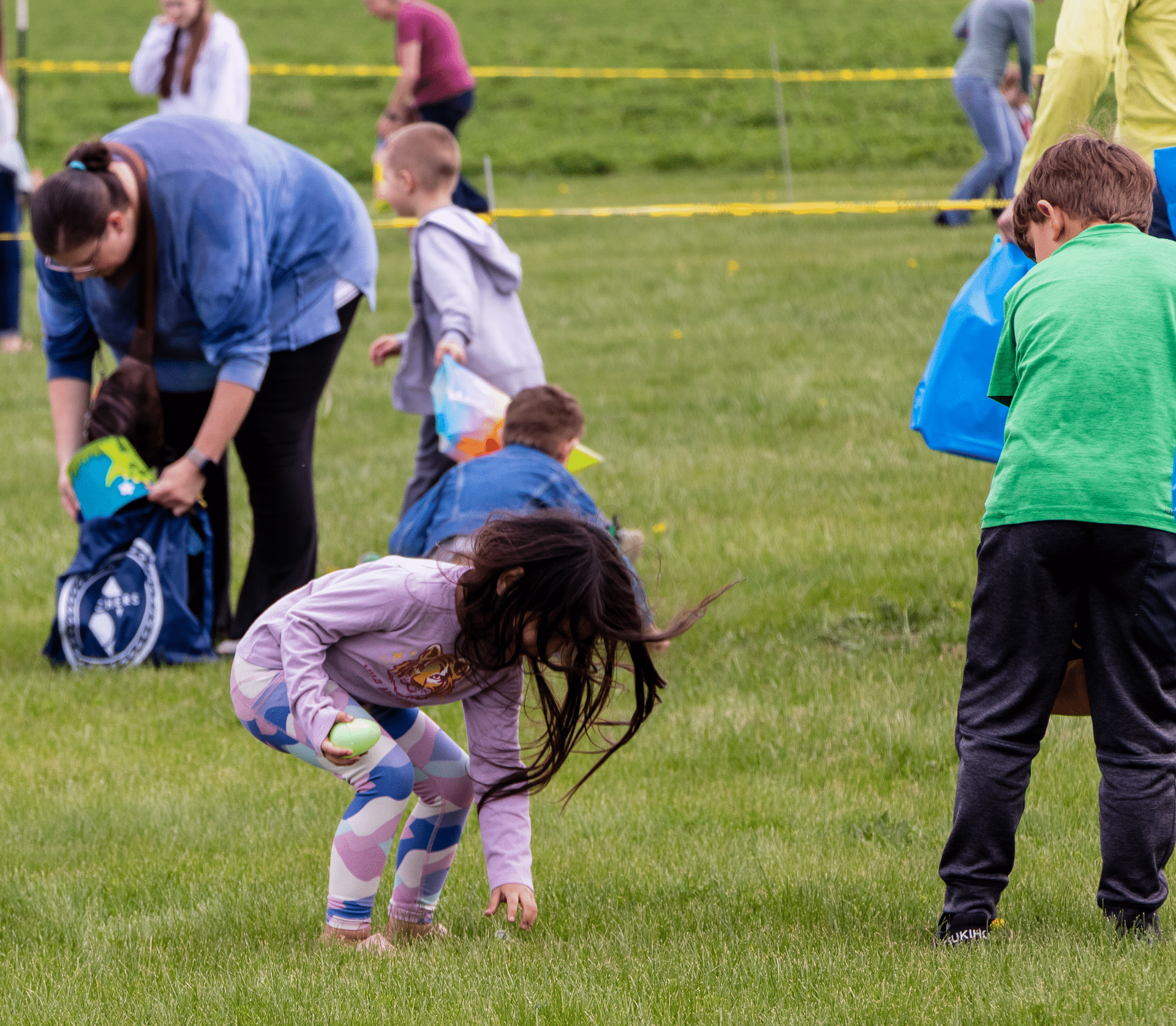 A joyful gathering of all ages on a sunny field, sharing laughter and hope as they collect treasures together. - Muscatine Church of Christ