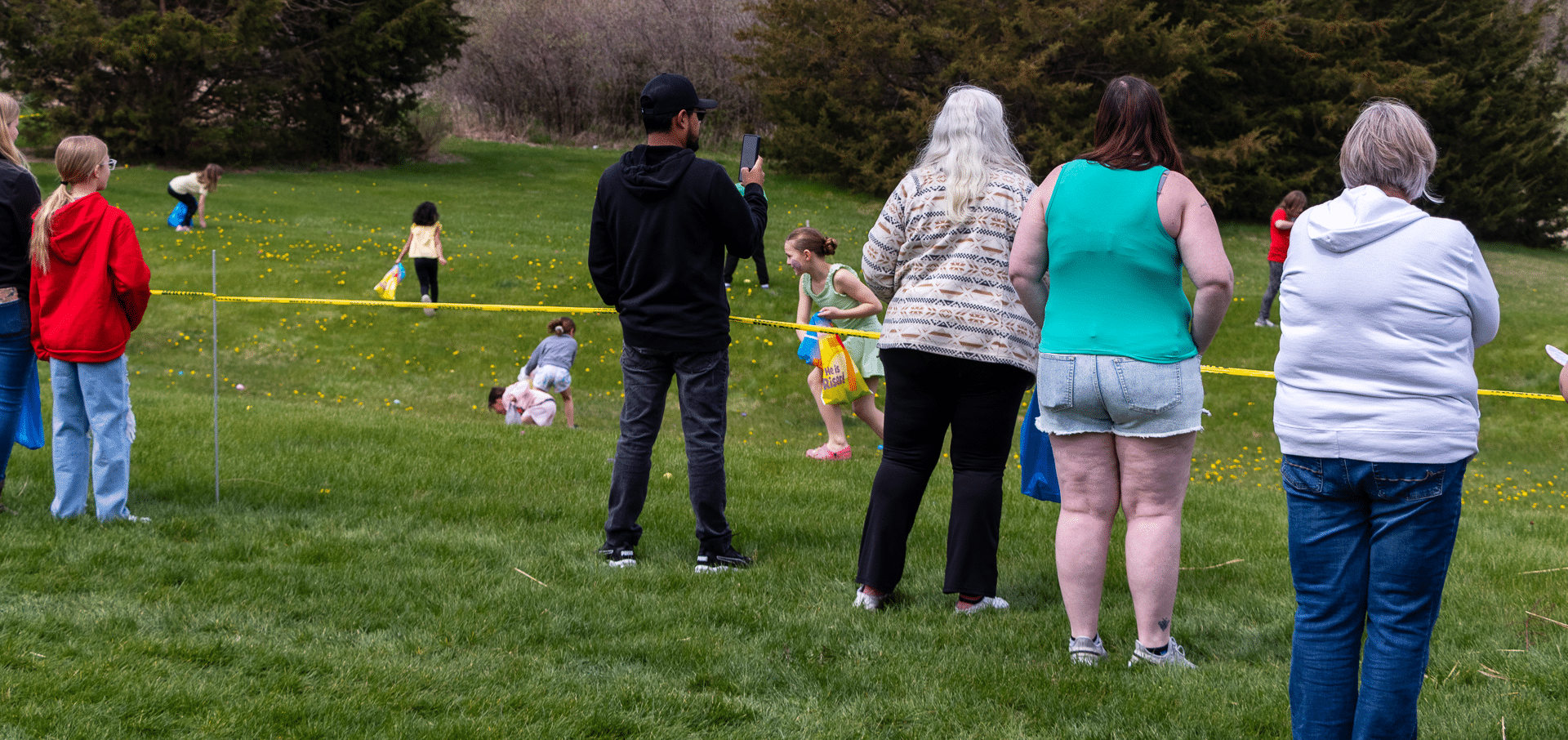 Adults and kids gather on a green field, sharing laughter and community at our joyful outdoor church event. - Muscatine Church of Christ