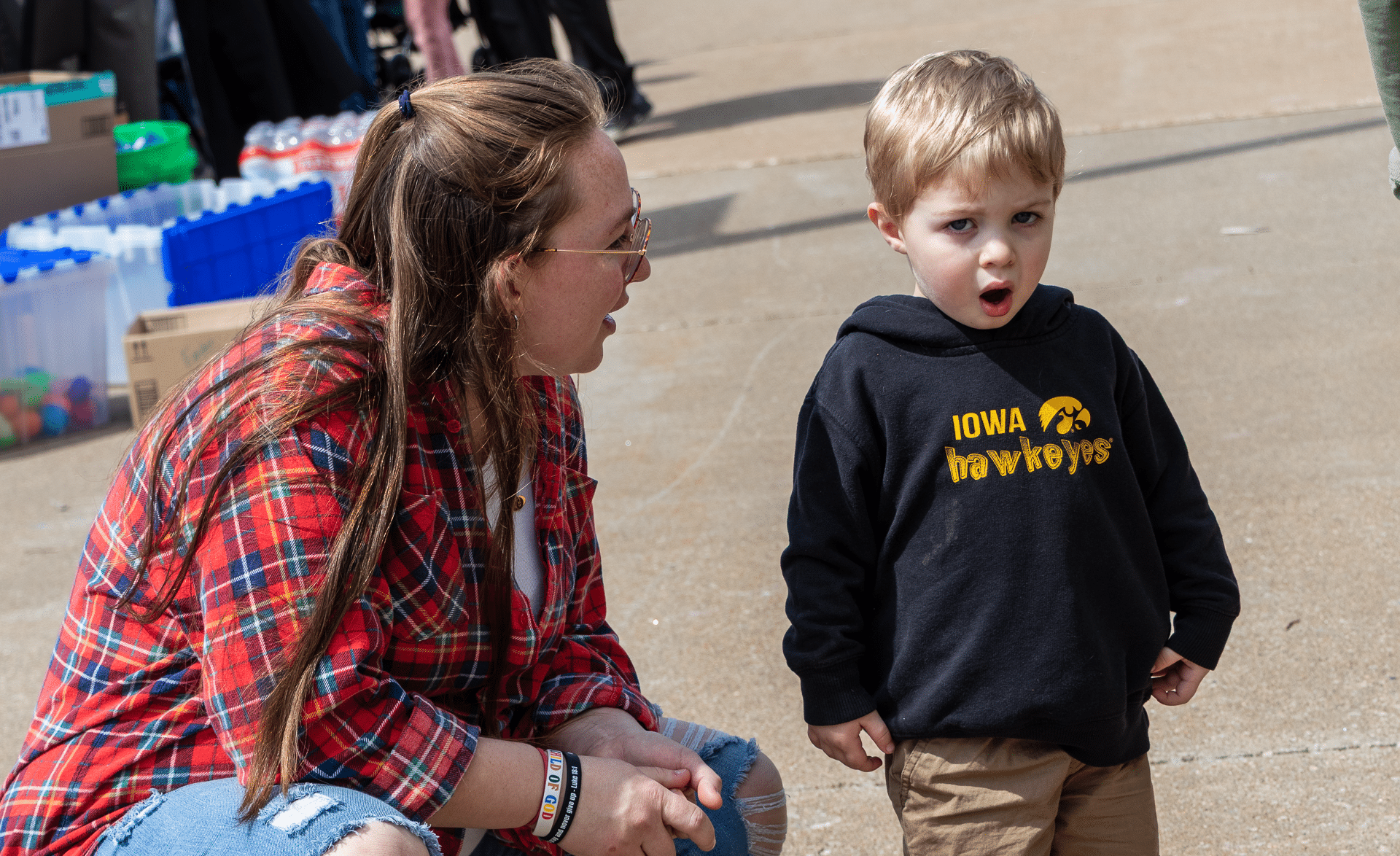 A caring adult and a child share a joyful, surprised moment together outside on a sunny day. All are welcome here!. - Muscatine Church of Christ