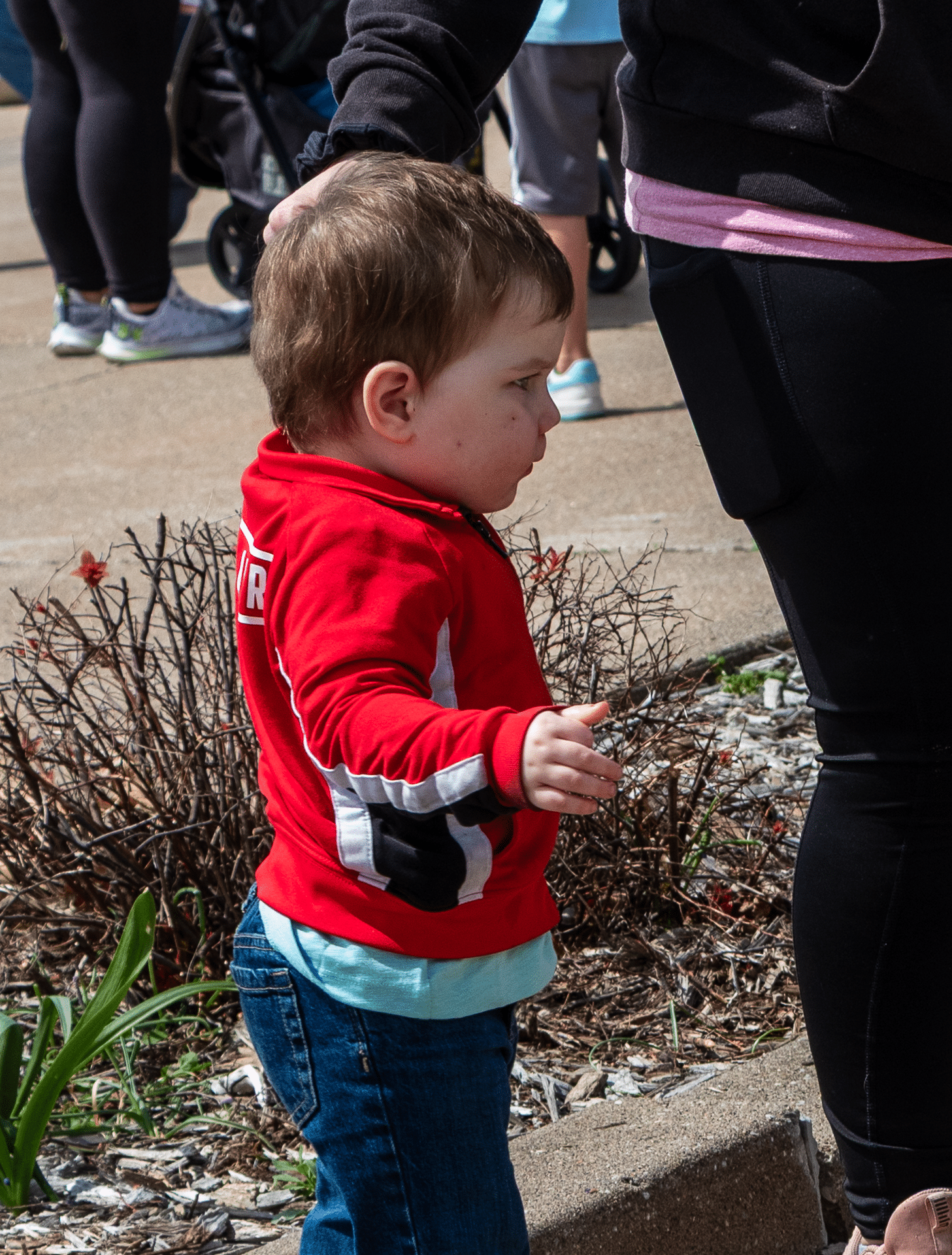 A caring adult gently encourages a child in red, sharing hope and belonging together in our church family outdoors. - Muscatine Church of Christ