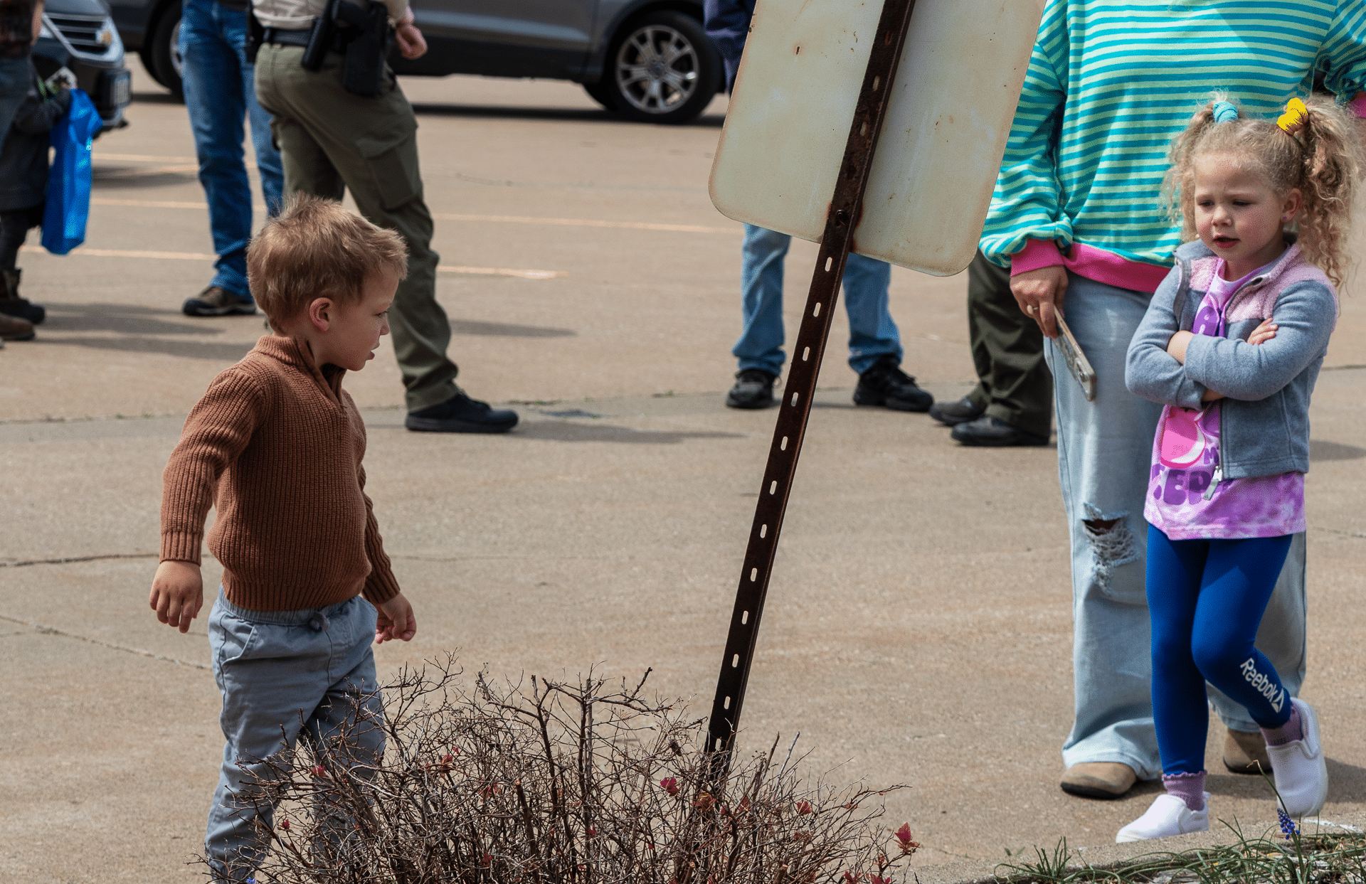 Two children smile together outside our church, with caring adults nearby—everyone welcome, hope in every heart. - Muscatine Church of Christ