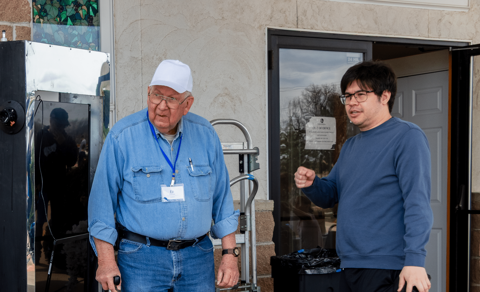 A welcoming older and younger man stand together outside church, ready to greet you with hope and friendship. - Muscatine Church of Christ