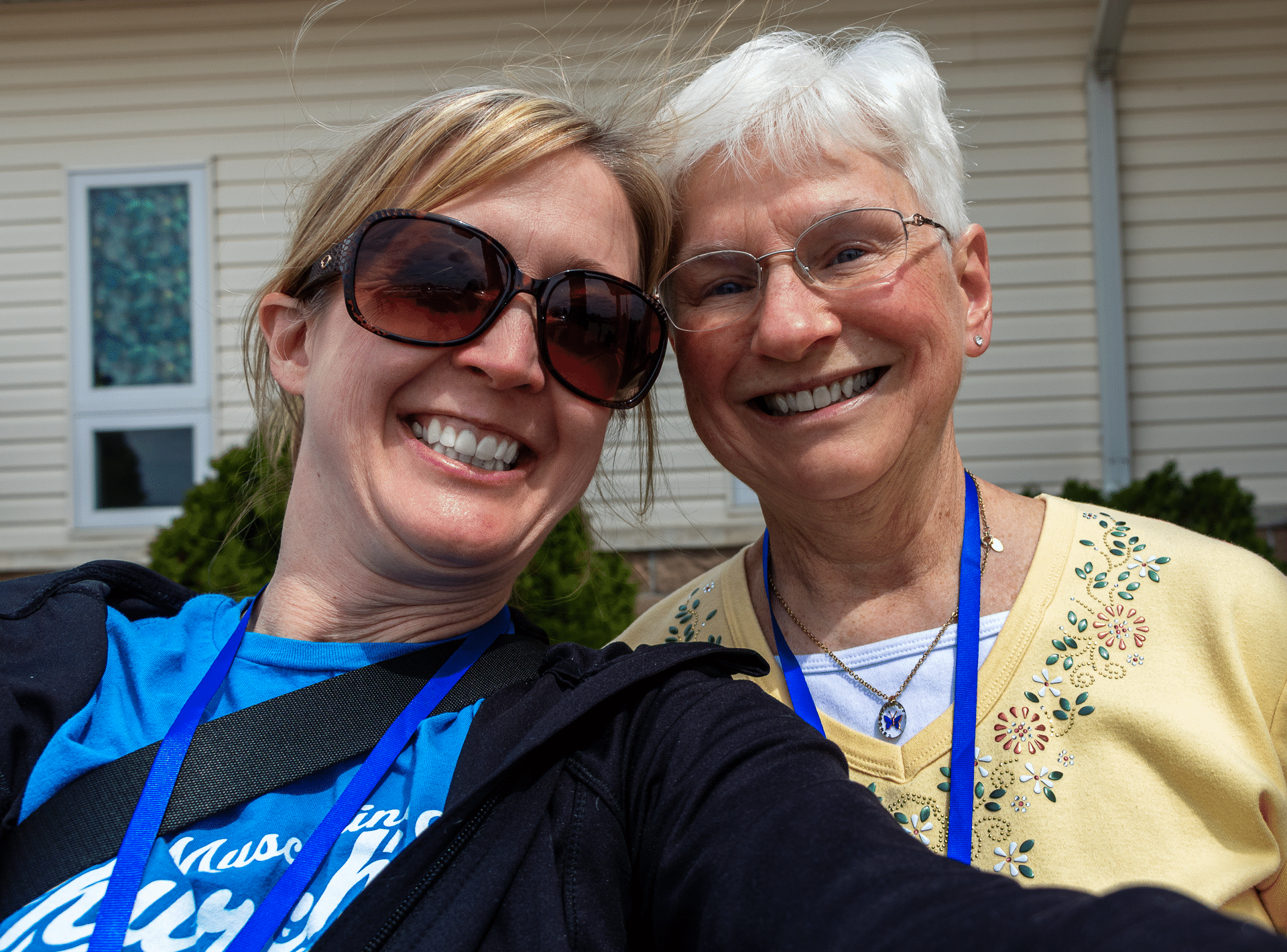 Two women share a joyful selfie outside our church, welcoming all with hope and friendship. - Muscatine Church of Christ
