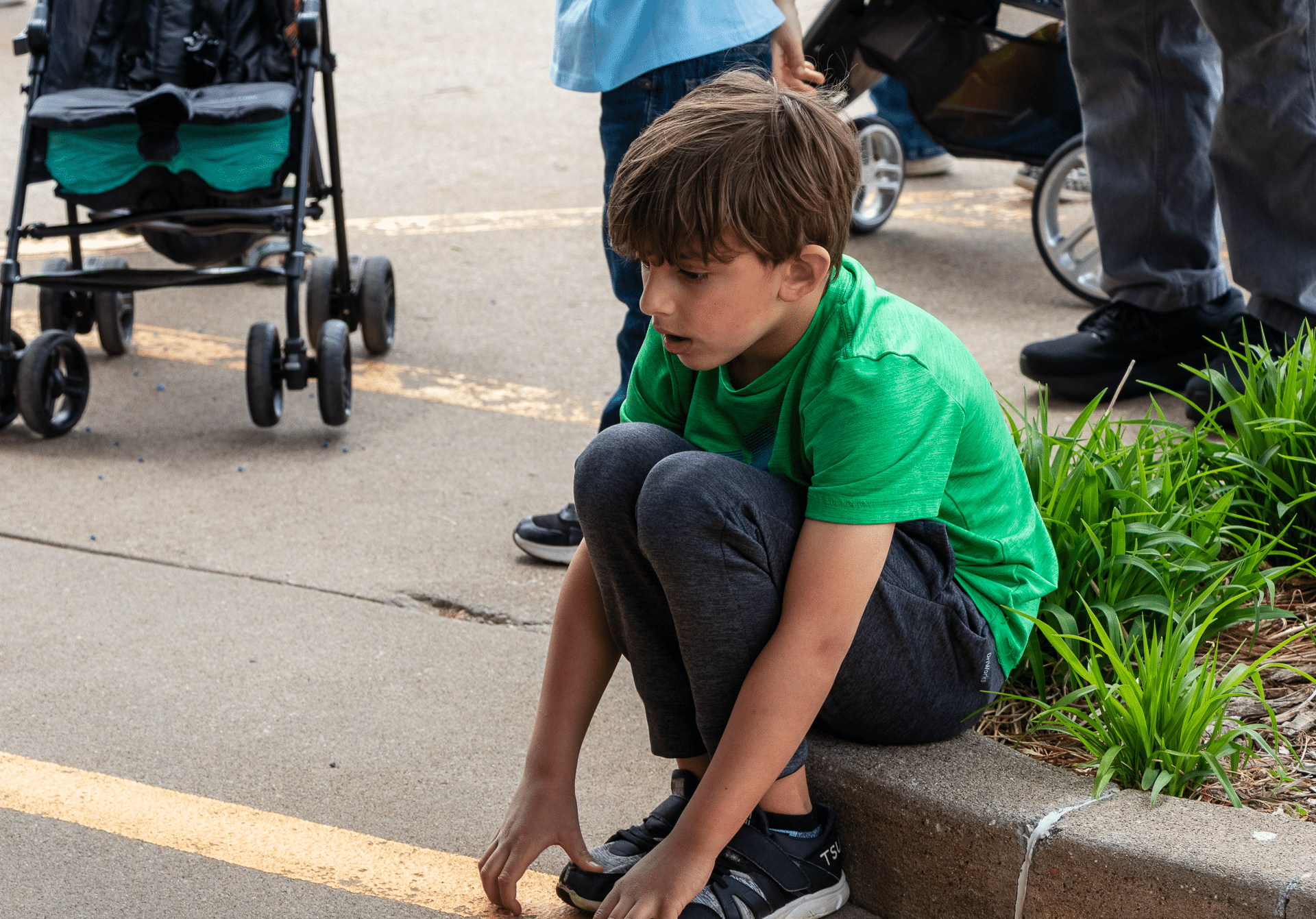 A boy in a green shirt sits on a curb, surrounded by a caring community, symbolizing welcome and hope for all. - Muscatine Church of Christ