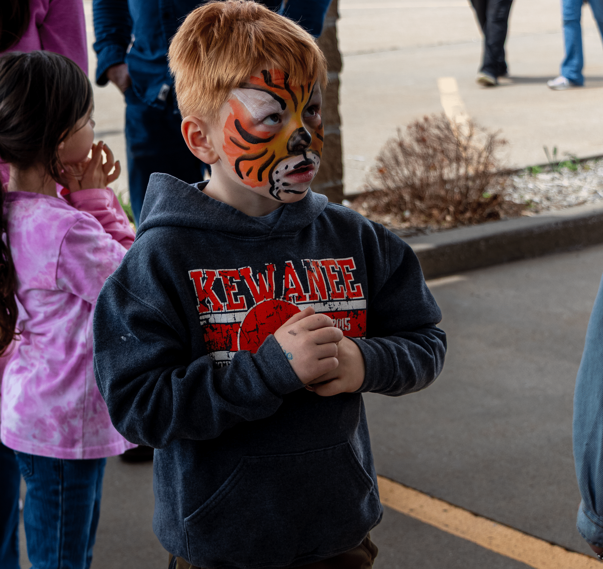 A smiling boy with tiger face paint joins friends outdoors, sharing joy and welcome at our Muscatine Church of Christ event. - Muscatine Church of Christ