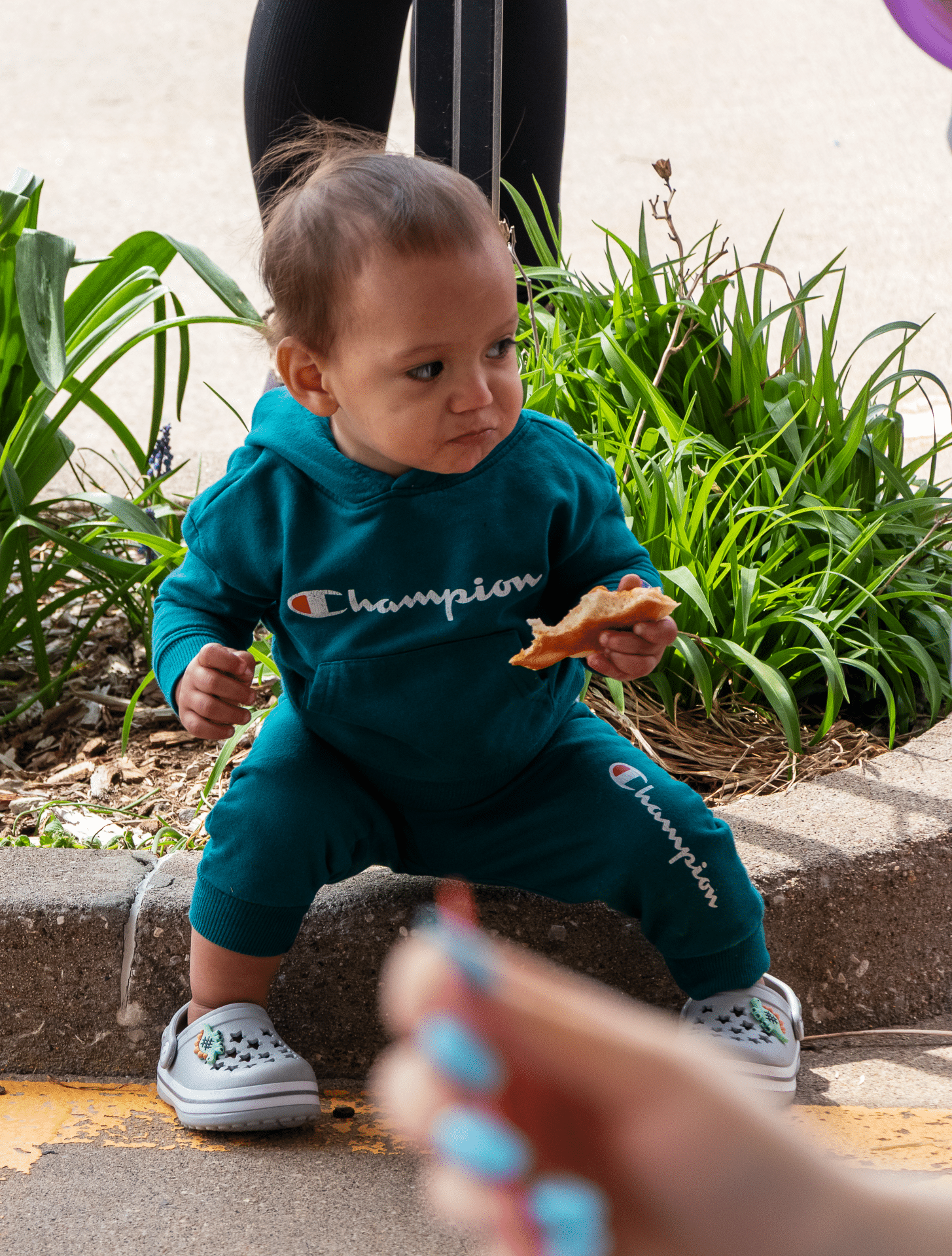 A toddler enjoys a snack on a sunny day, surrounded by caring community and the promise of hope. - Muscatine Church of Christ
